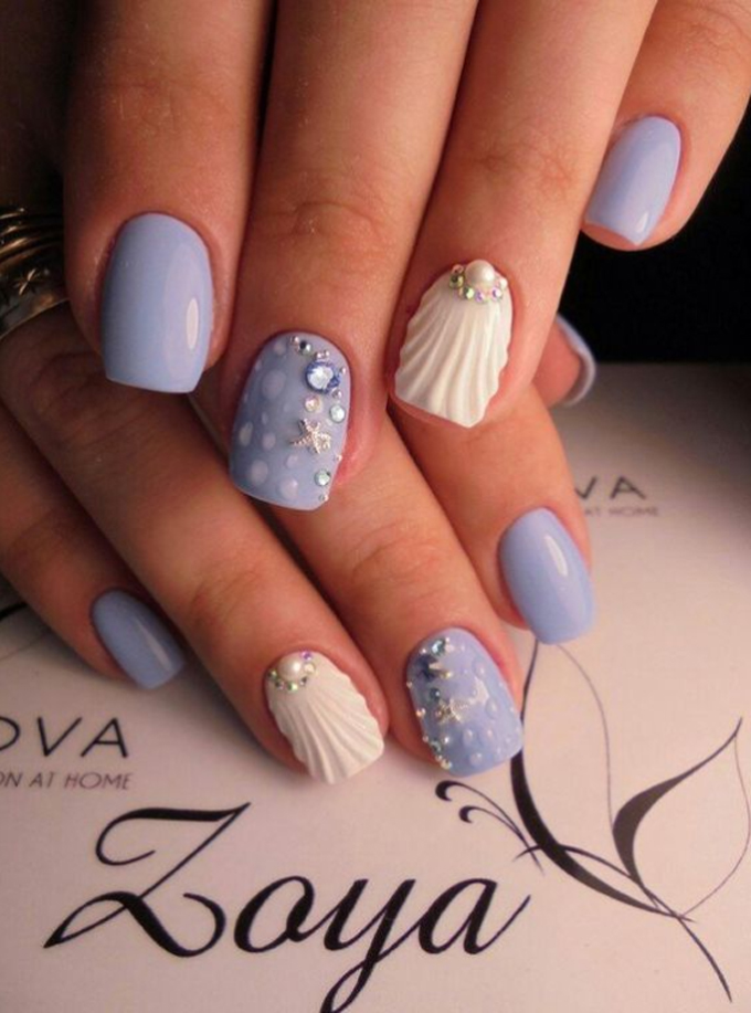 Uñas de diferentes tonos de azul con detalles de conchas marinas y estrellas de mar