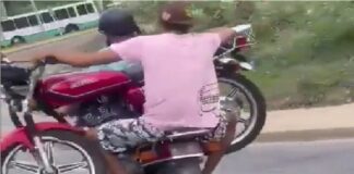 Dos motorizados cargan moto La Guaira
